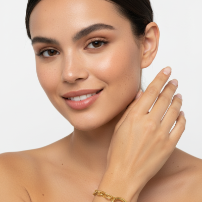 Pulseira dourada com pendente circular num pulso feminino em fundo branco