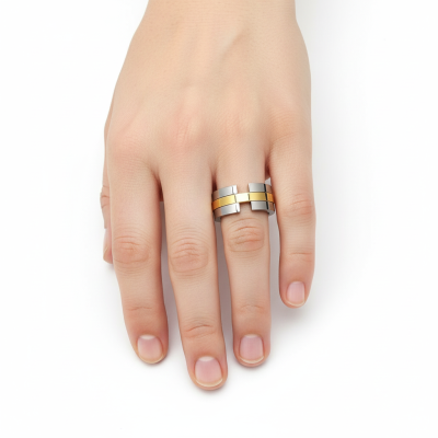 Anel moderno em metal prateado com detalhes dourados numa mão sobre fundo branco