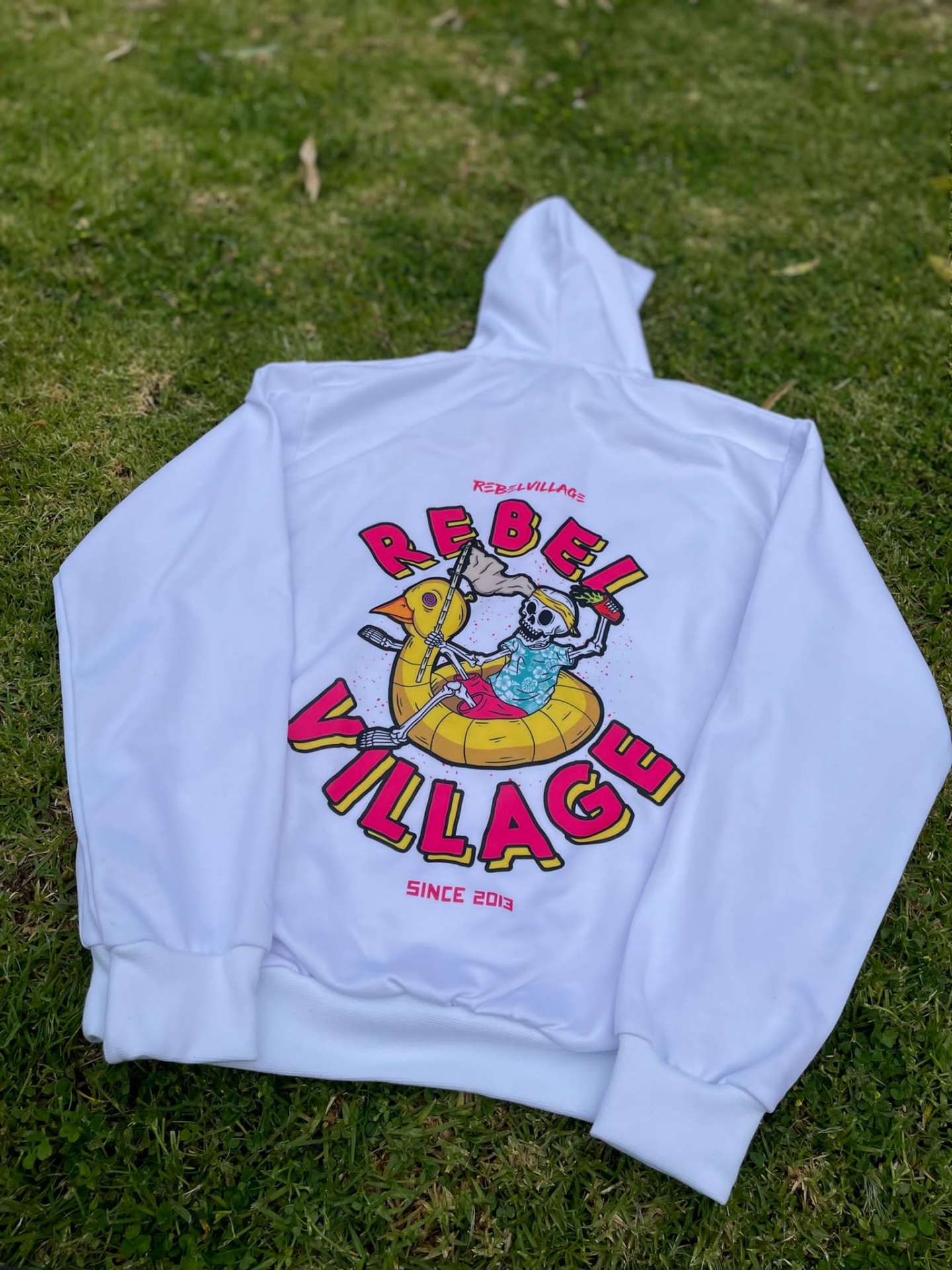 Sweatshirt branca com estampa colorida nas costas sobre relva