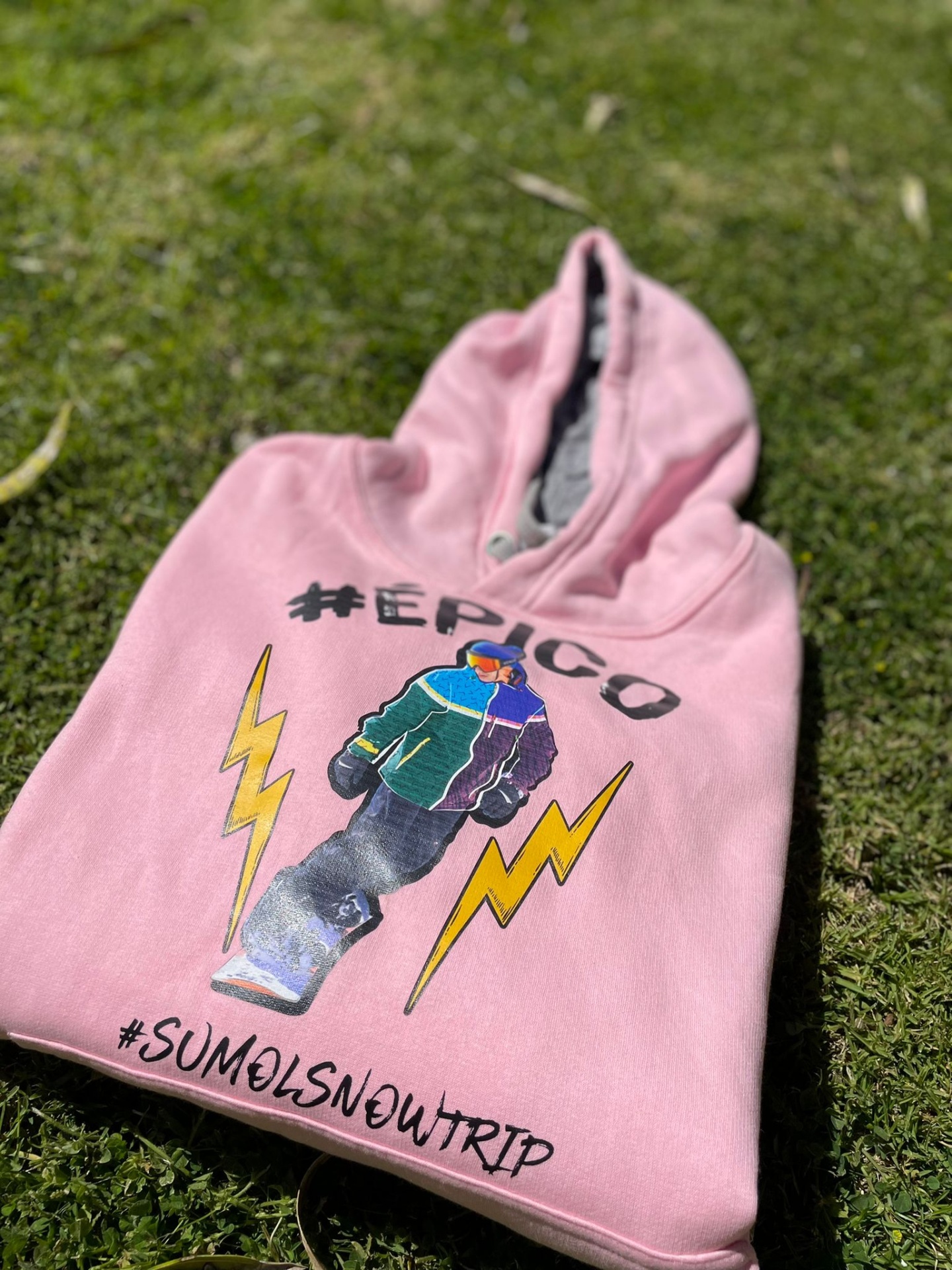 Camisola cor-de-rosa com capuz e estampa colorida sobre relva verde