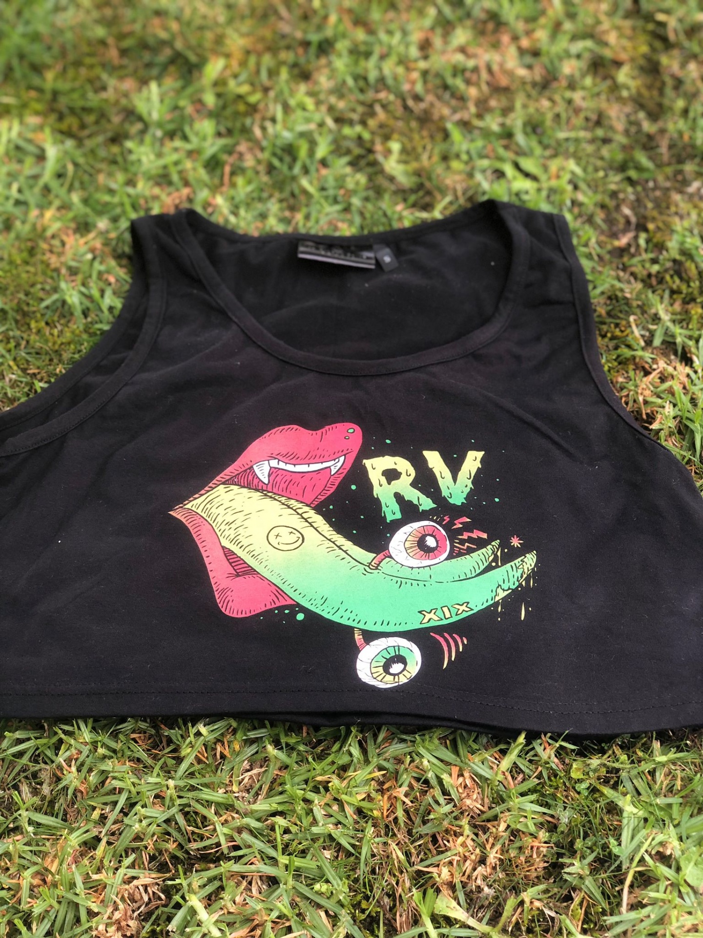 Top cropped preto com estampa colorida de boca, olho e skate sobre relvado