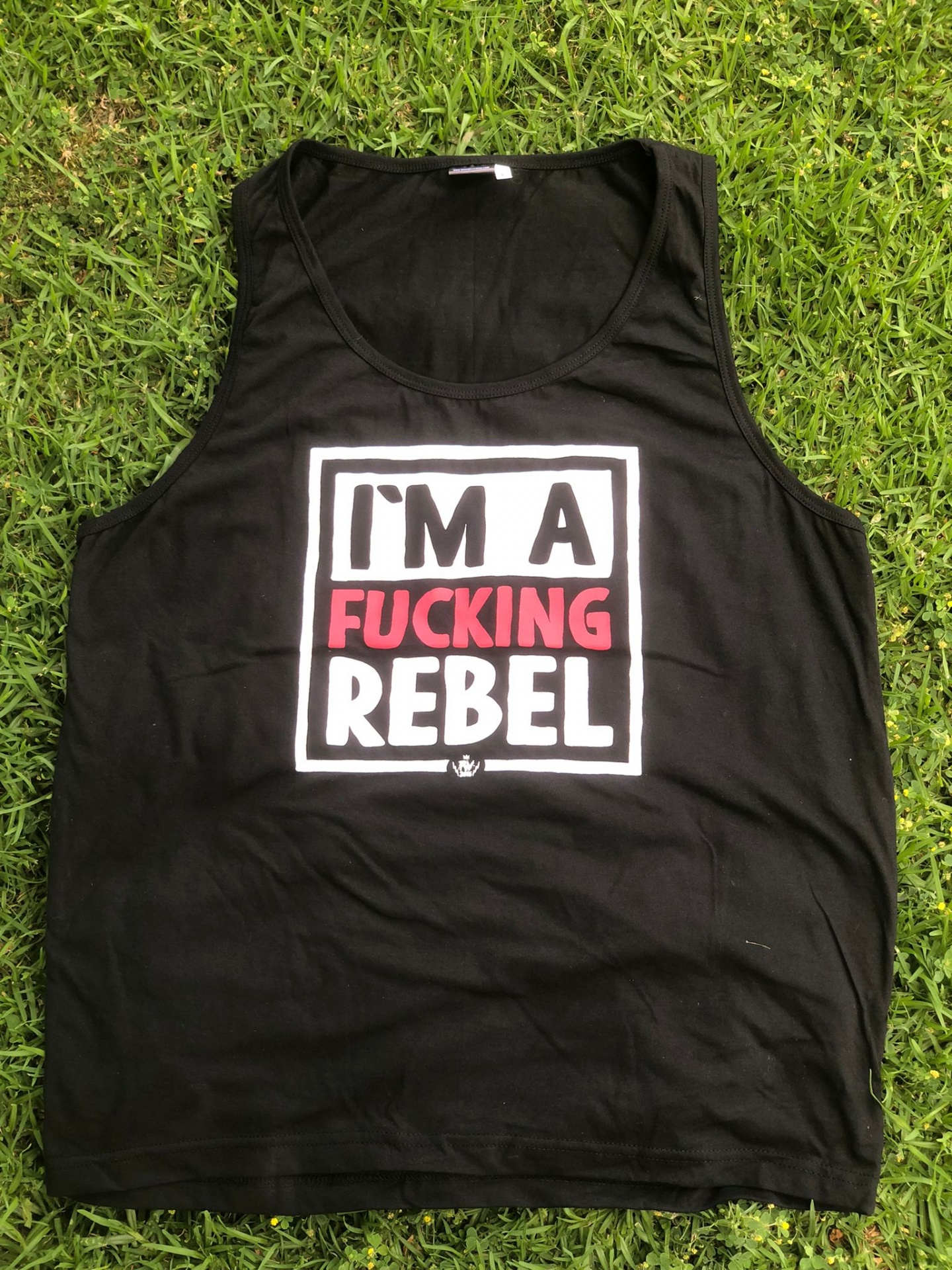 Camisola preta sem mangas com estampa em branco e vermelho I'M A FUCKING REBEL sobre relva.