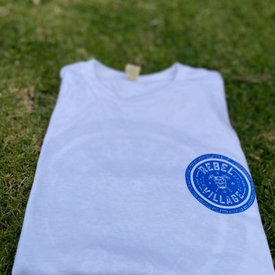 Camiseta branca com estampado azul REBEL VILLAGE sobre relva