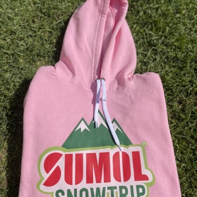 Camisola com capuz rosa com estampa SUMOL SNOWTRIP e montanhas, sobre relva