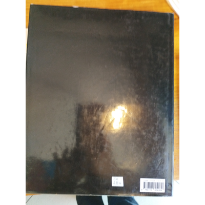 Livro ou caderno com capa preta brilhante e etiqueta com código de barras numa mesa de madeira