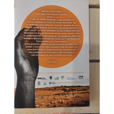 Capa de livro com texto em círculo laranja, mão esquerda em preto e branco e paisagem de terra seca