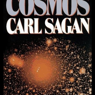 Capa do livro Cosmos de Carl Sagan com fundo preto e manchas alaranjadas brilhantes