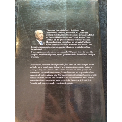Contracapa de livro castanho escuro com foto preta e branca e texto descritivo em português sobre Shimon Peres