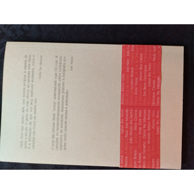 Parte traseira de livro com capa dura castanha e faixa vermelha com nomes em branco