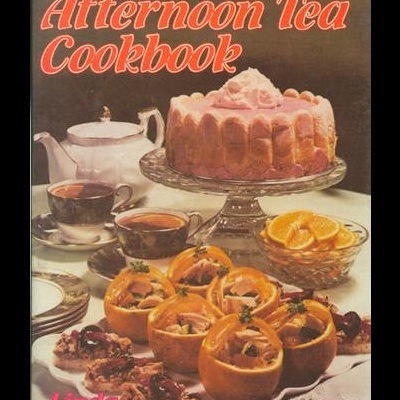 Capa do livro de receitas com bolos, chá e petiscos sobre mesa
