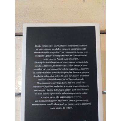 Livro com capa preta e texto branco sobre fundo de madeira clara