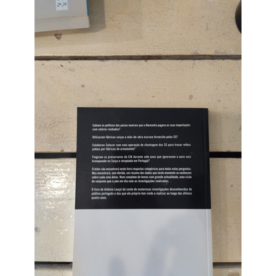 Livro com capa branca e preta com texto em português sobre superfície de madeira clara