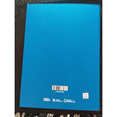 Livro com capa azul com códigos e logos na parte inferior, sobre mesa de madeira clara