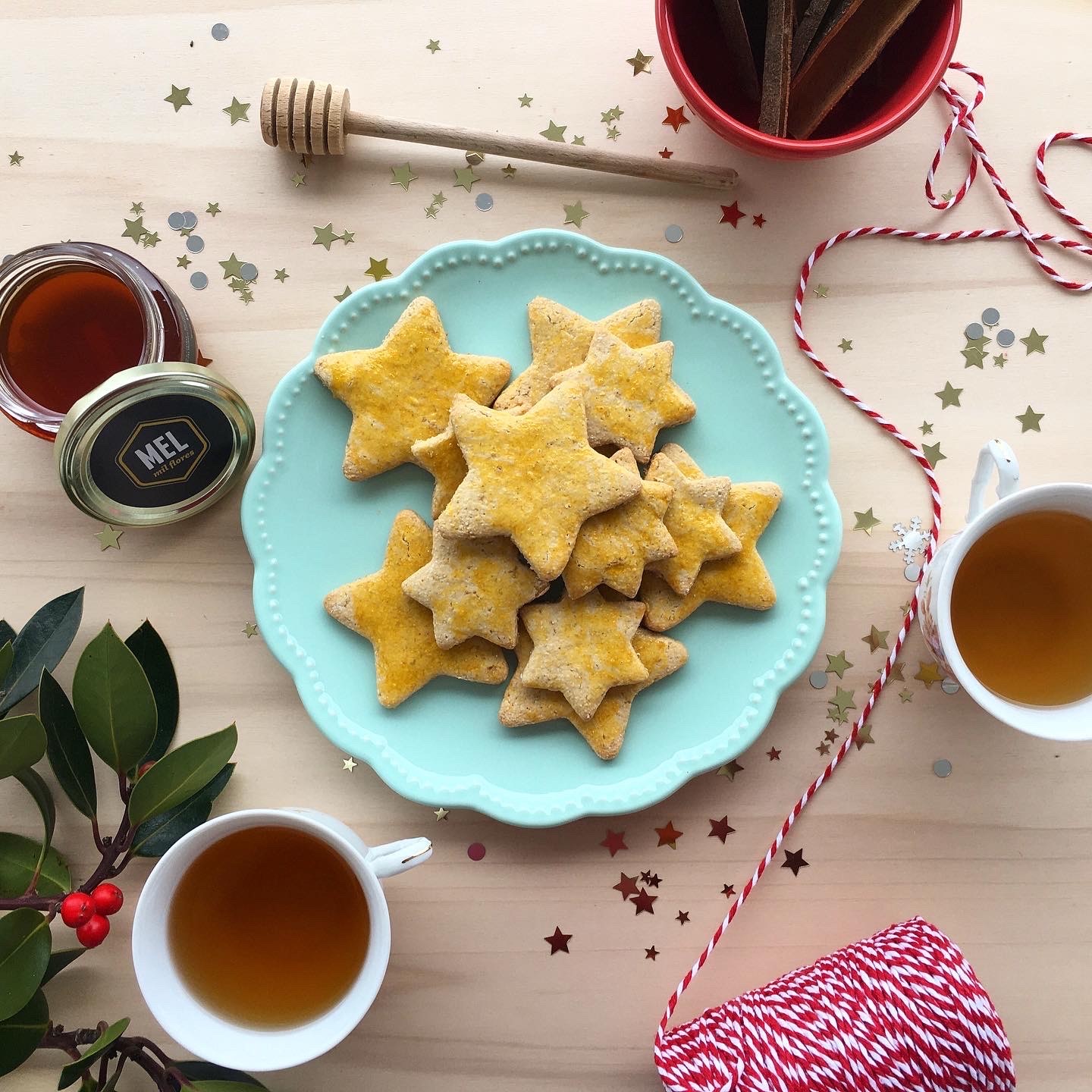 Biscoitos em forma de estrela num prato azul com chá e mel numa mesa decorada