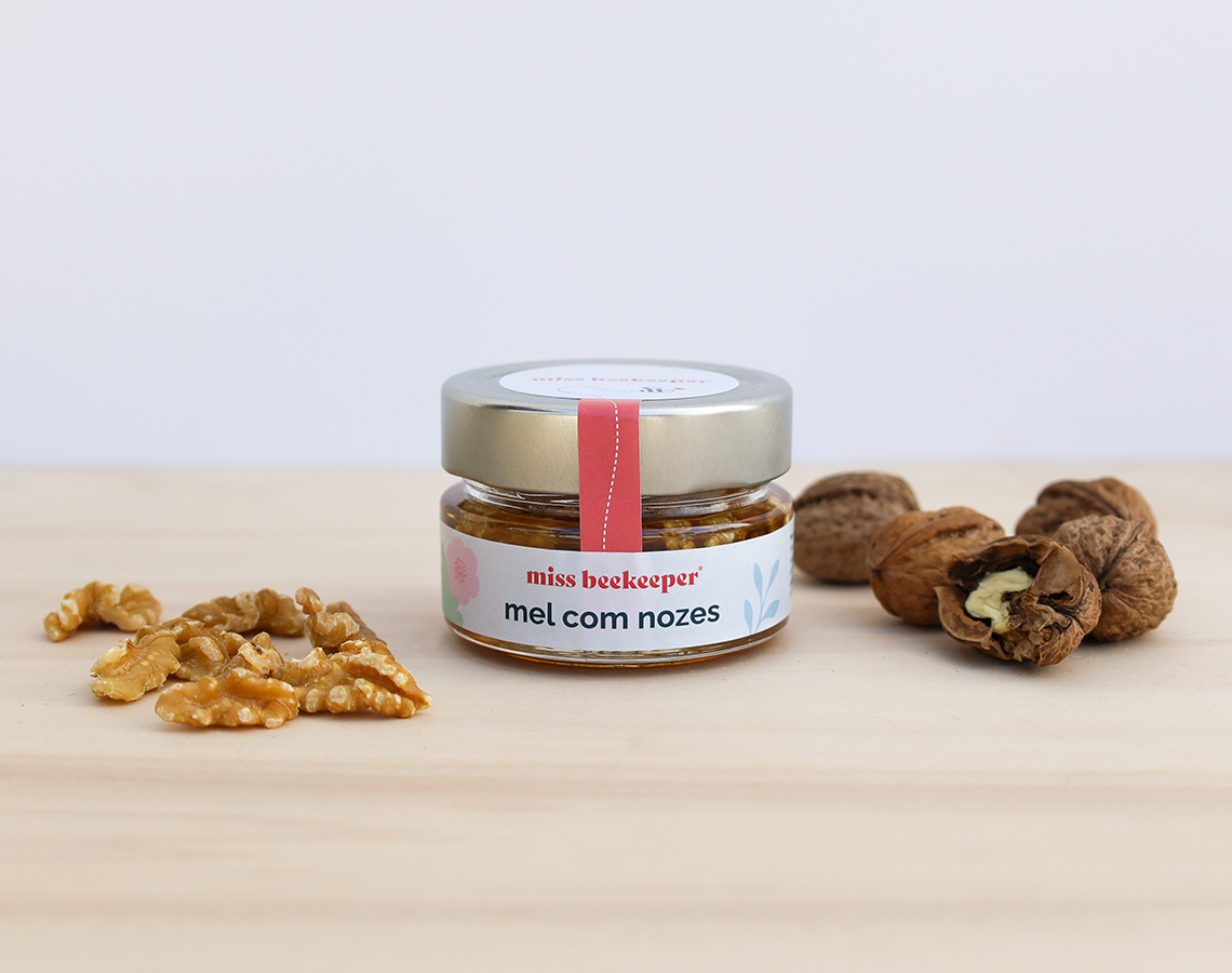 Frasco de mel com nozes junto a nozes inteiras e descascadas