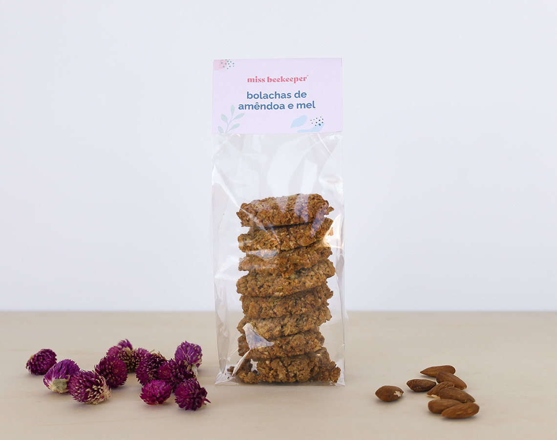 Pacote transparente de bolachas com etiqueta branca e lilás, flores secas roxas e amêndoas