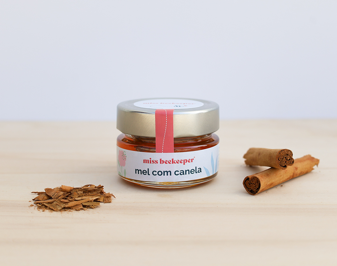Frasco de mel com canela, paus e lascas de canela sobre madeira
