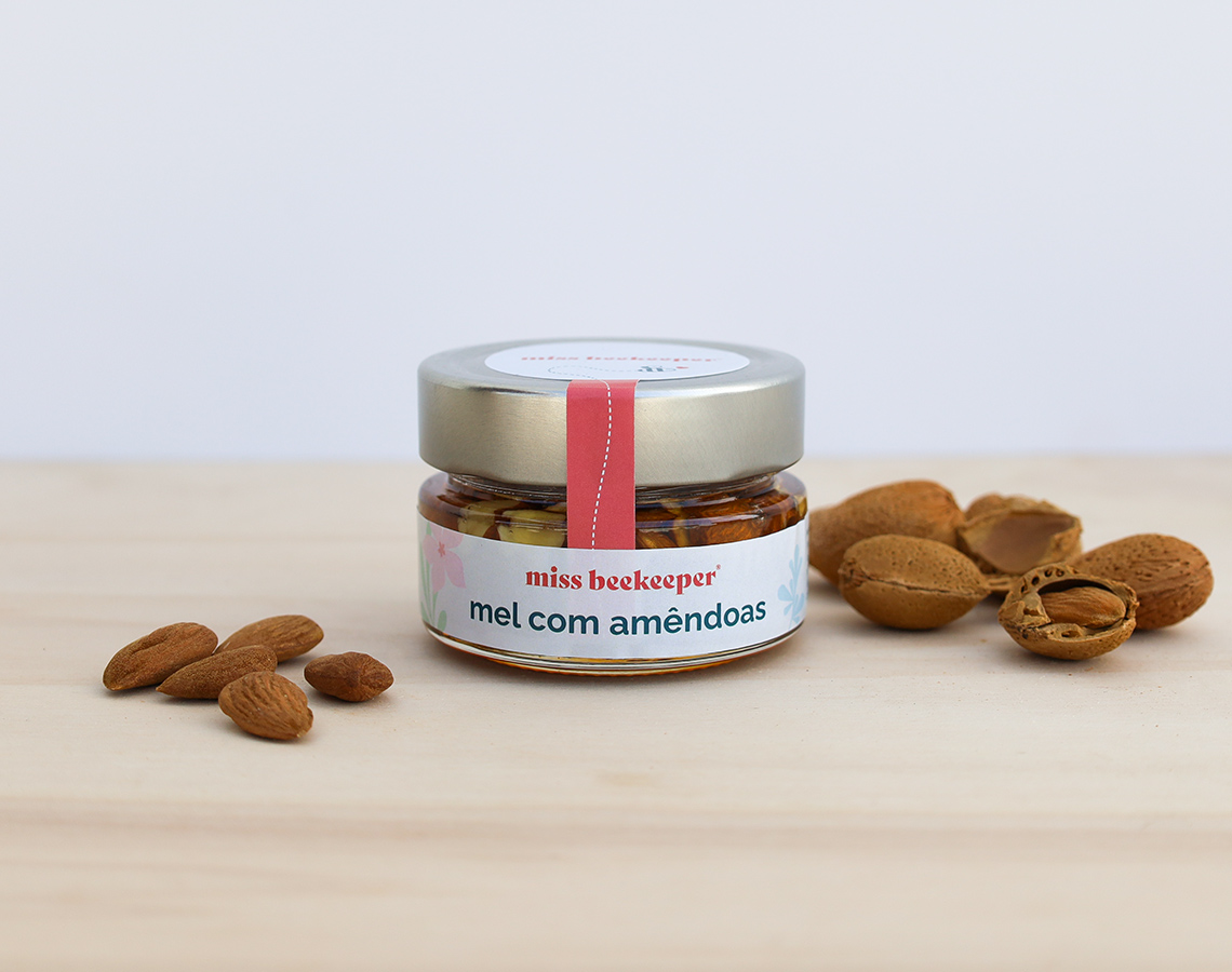 Frasco de mel com amêndoas e amêndoas ao redor sobre madeira
