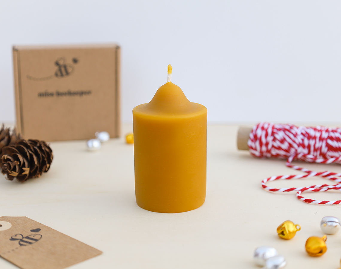 Vela cilíndrica amarela de cera com pavio rodeada por acessórios de decoração