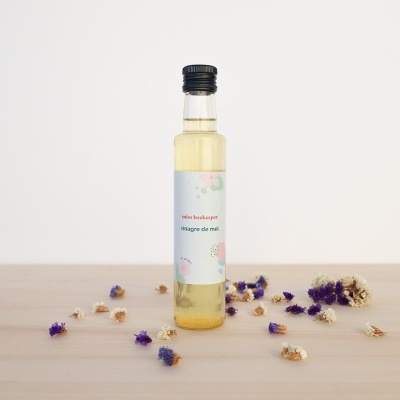 Frasco de vidro com vinagre de mel e flores secas numa mesa de madeira