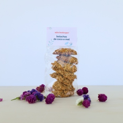 Pacote transparente de bolachas de coco e mel com flores coloridas à sua volta