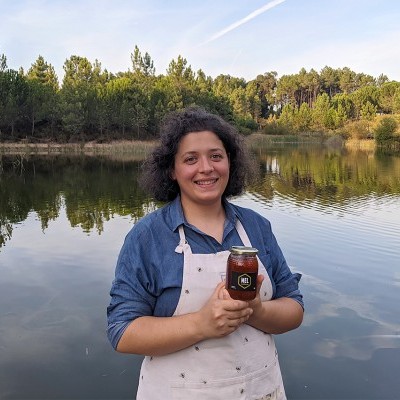 Mulher com avental segurando frasco de vidro em frente a lago com árvores