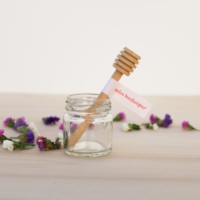 Frasco de vidro com colher de mel de madeira e flores secas
