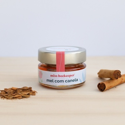 Frasco de mel com canela, paus e lascas de canela sobre madeira