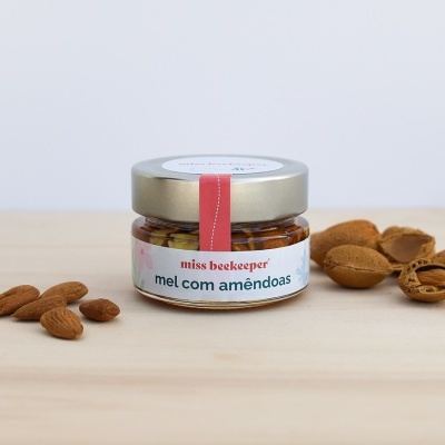 Frasco de mel com amêndoas e amêndoas ao redor sobre madeira