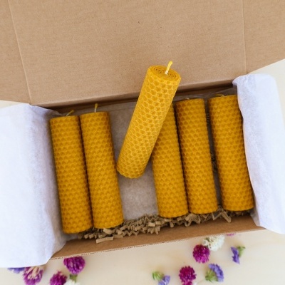 Sete velas amarelas de cera de abelha numa caixa de cartão com flores secas ao redor