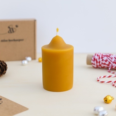 Vela cilíndrica amarela de cera com pavio rodeada por acessórios de decoração
