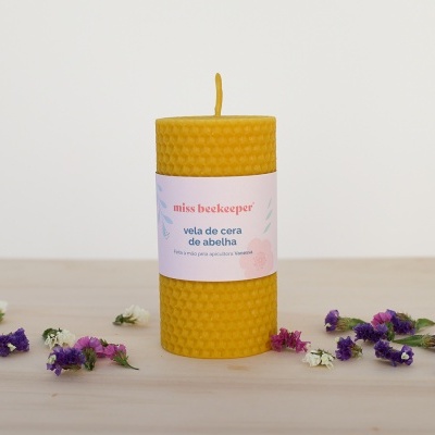 Vela de cera de abelha amarela com etiqueta miss beekeeper e flores secas