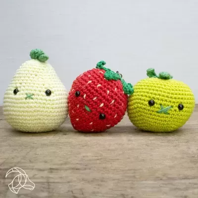 Bonecos de croché em forma de frutas: pêra, morango e maçã em cores amarelo claro, vermelho e verde.