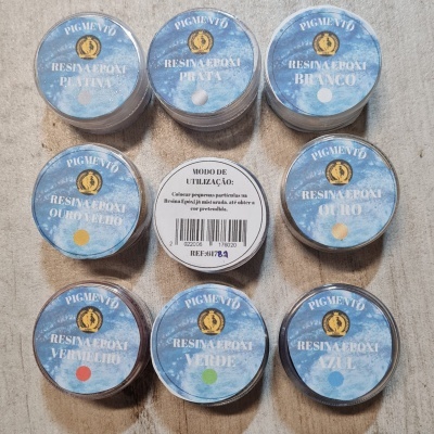 Conjunto de potes de resina epóxi Pigmento com diferentes cores em tampas azuis, sobre uma superfície clara