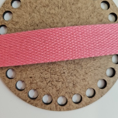 Disco castanho com buracos e fita rosa de tecido em fundo branco
