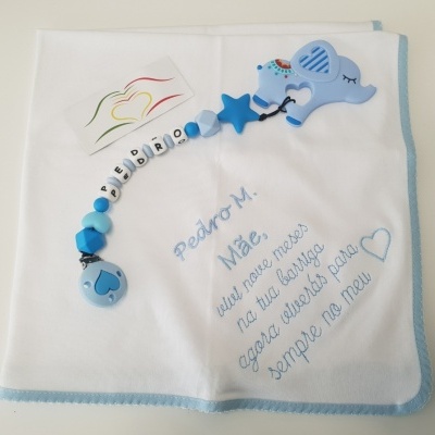 Fralda branca com bordado azul e prendedor de chucha azul com elefante de silicone.