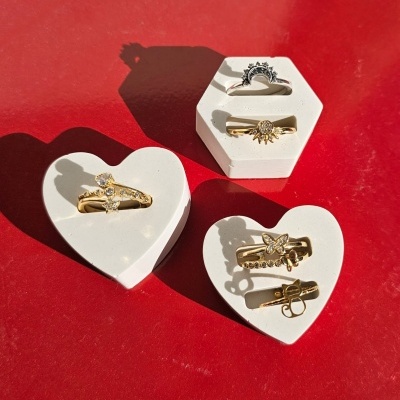 Quatro anéis decorativos em suportes brancos sobre fundo vermelho