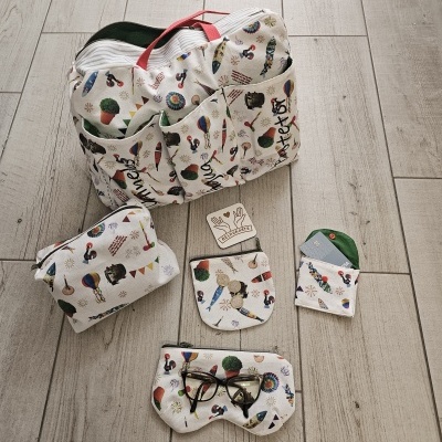 Conjunto de bolsa e acessórios em tecido branco com padrão colorido de animais e balões