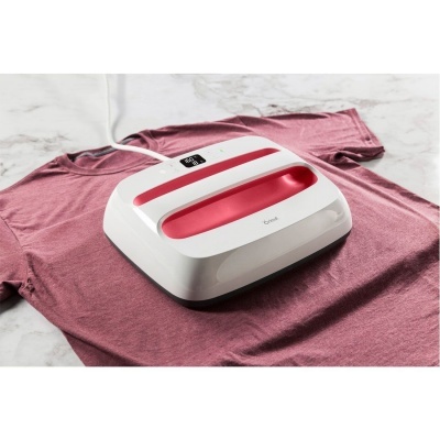 Prensa térmica branca e vermelha sobre t-shirt rosa em chão de mármore