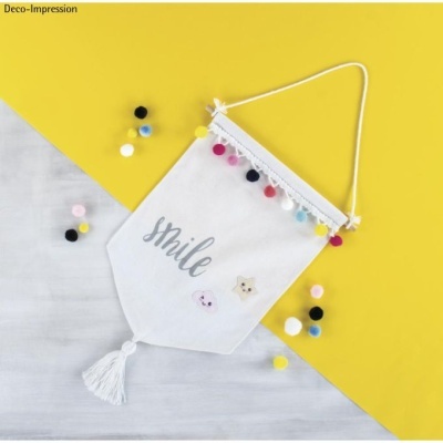 Pendurador de parede em tecido branco com decoração colorida e texto 'smile'.