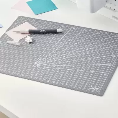 Tapete de corte cinza com gradações num fundo de mesa branca e objetos de corte