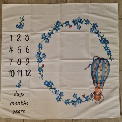 pano branco com números, texto e desenho de balão com personagem e flores azuis