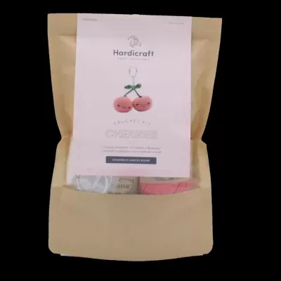 Embalagem de papel kraft com etiqueta branca e imagem de duas cerejas tricotadas vermelhas.