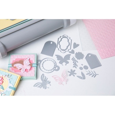 Moldes de corte em metal de vários formatos e papel texturizado cor-de-rosa com cadernos decorados