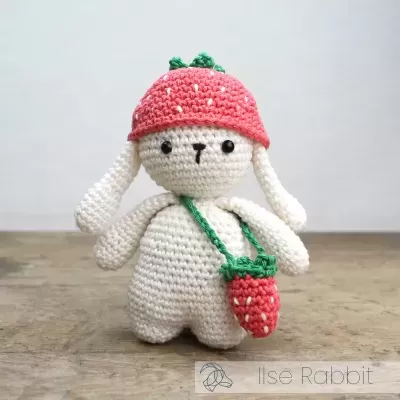 Boneco de crochê com chapéu e bolsa em forma de morango