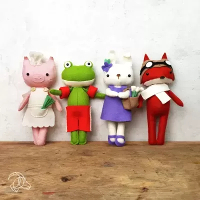 Quatro bonecos de peluche de animais em pé sobre madeira com fundo branco