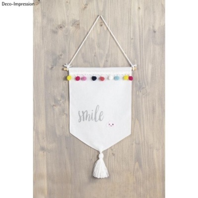 Pendurante branco com pompons coloridos e palavra 'smile' suspenso numa parede de madeira