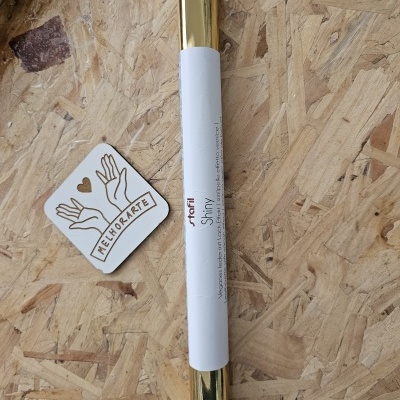 Rolo de papel autocolante dourado brilhante com etiqueta branca e etiqueta MELHOMARTE sobre madeira