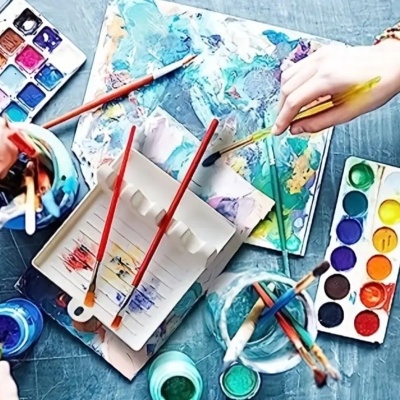 Mesa com material de pintura em aquarela com pincéis e paleta colorida