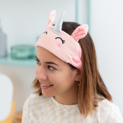 Faixa de cabelo cor-de-rosa com chifre de unicórnio usada por mulher